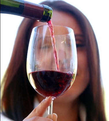A woman holding a wine glass that is being filled